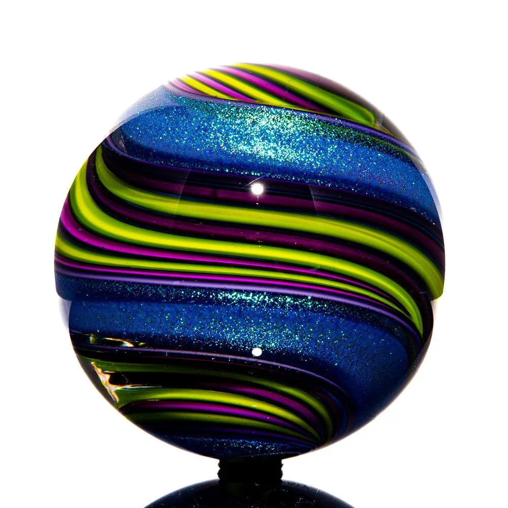 Handcrafted glass marble with blue glitter and swirling green, yellow, and purple bands