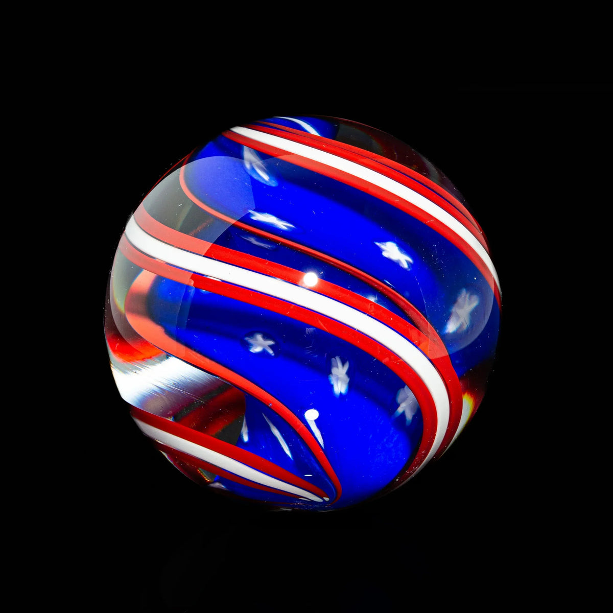 Colorful glass marble with red, white, and blue swirls on a black background.