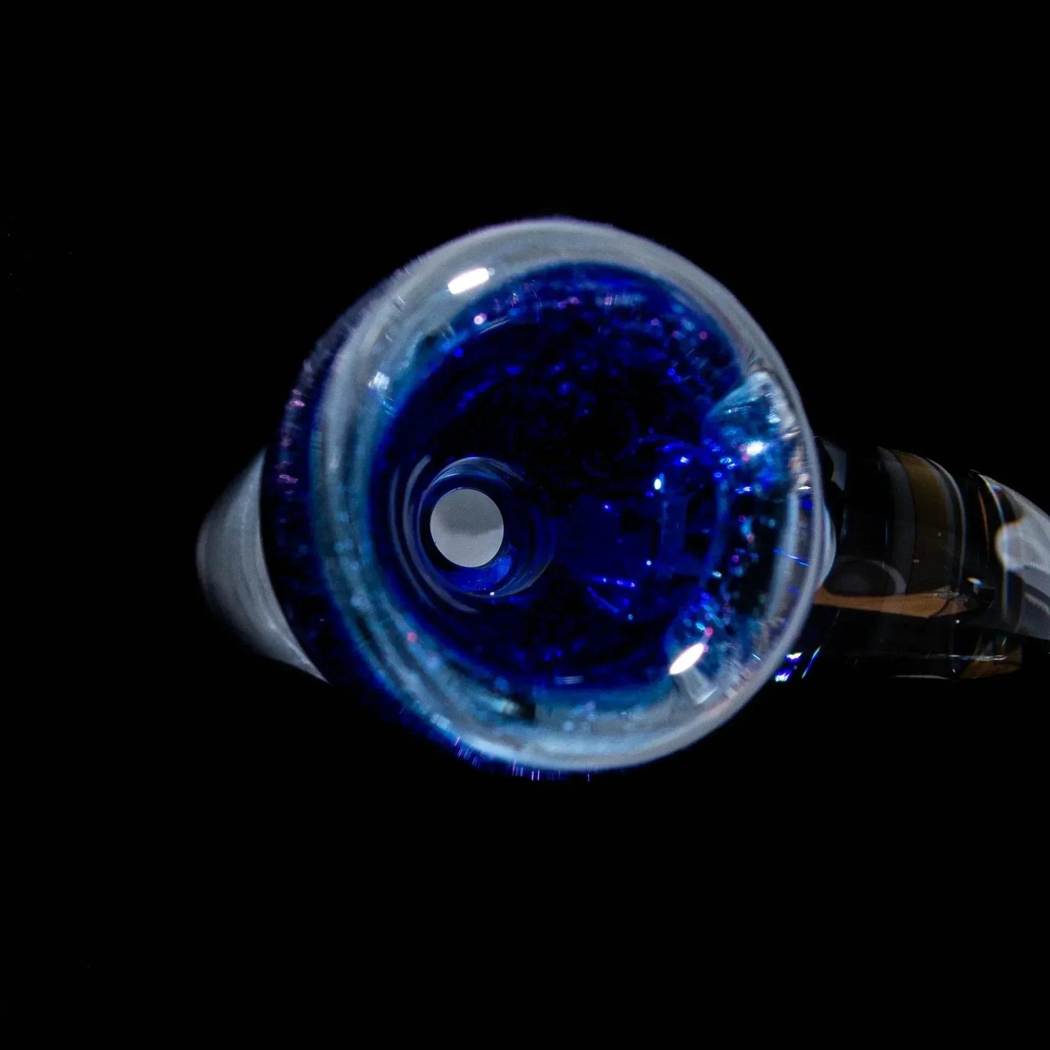 Top view of a blue glass slide bowl with flared rim and sparkly accents on black background