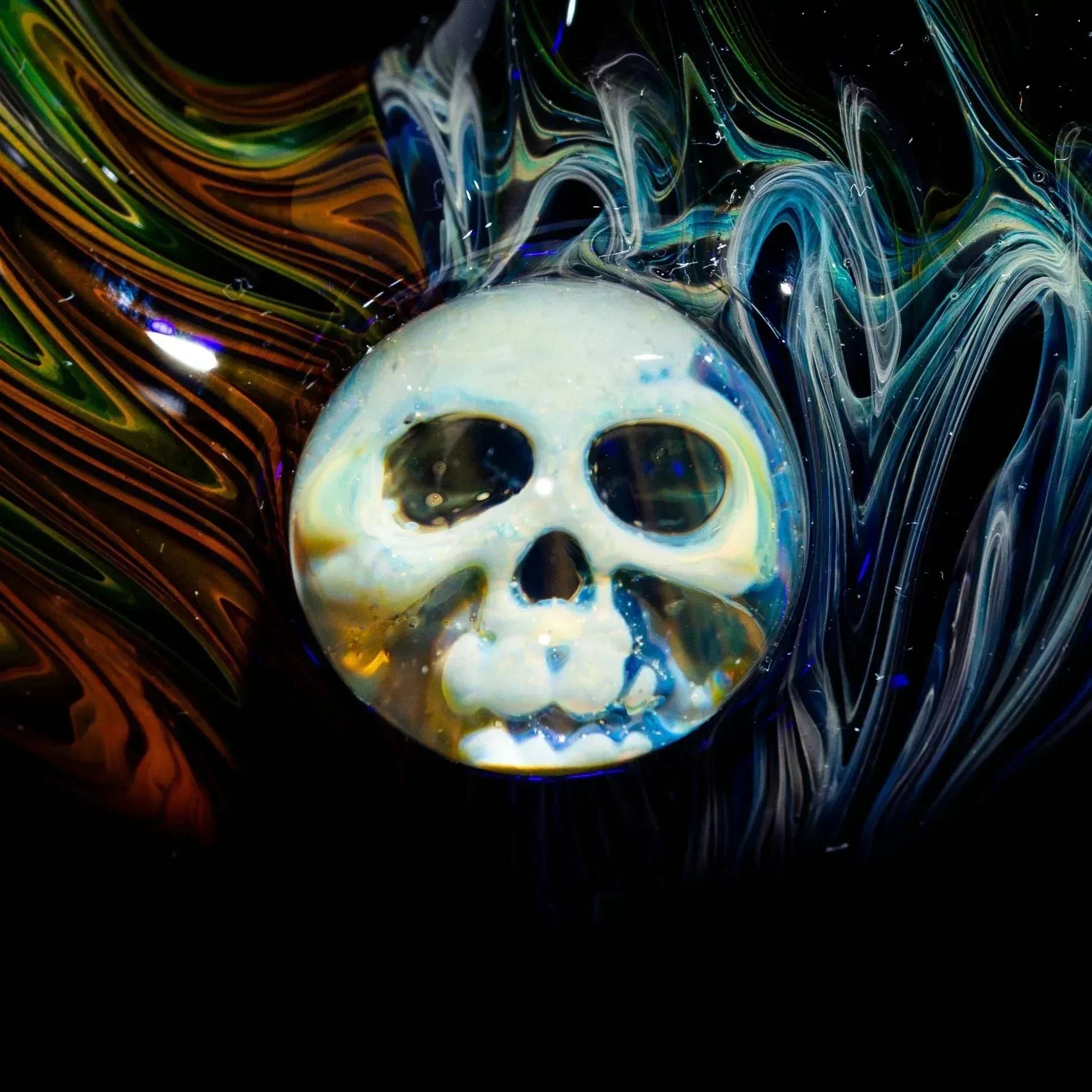 Close-up of a glass pipe featuring a skull design and vibrant swirling colors