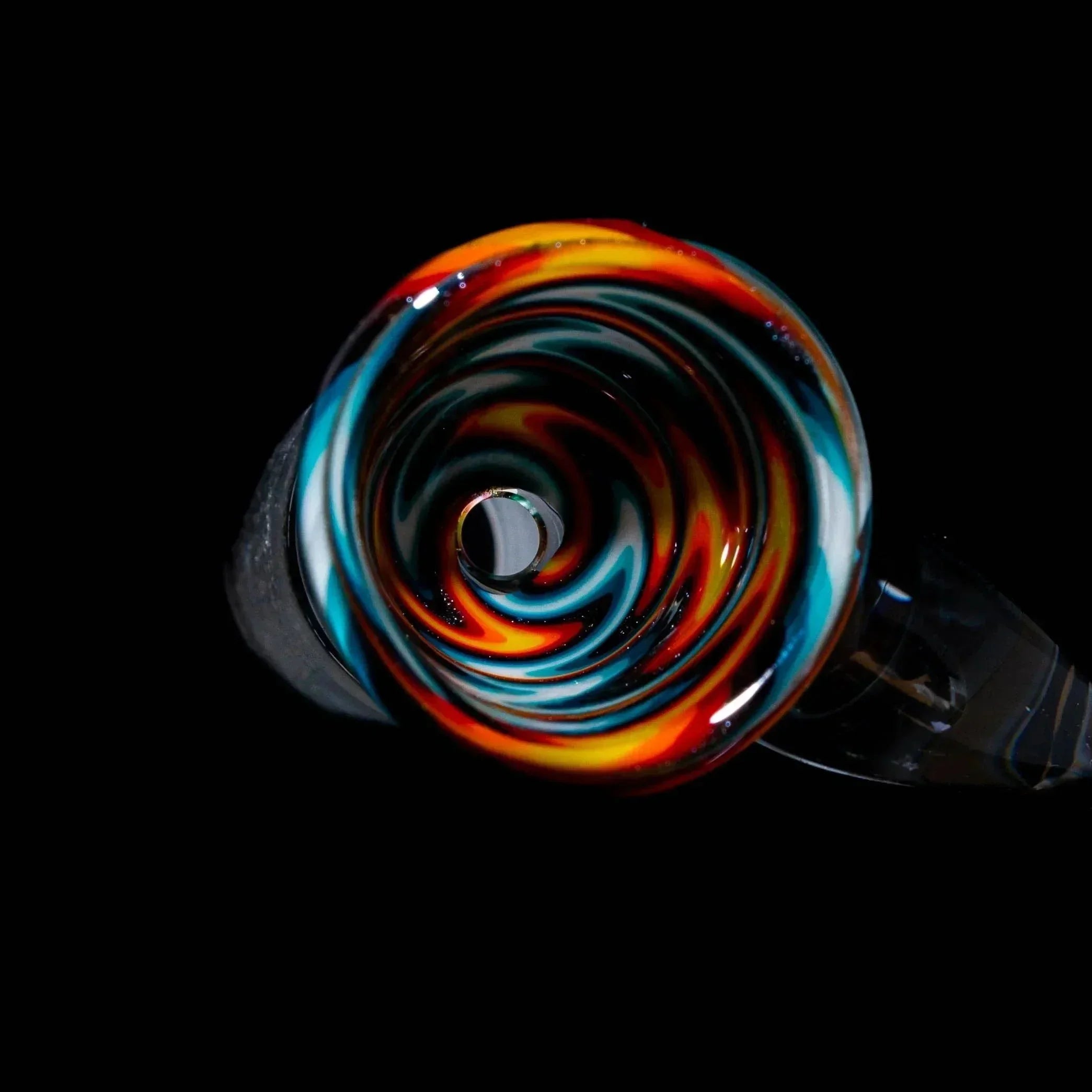 Colorful glass slide bowl with blue, orange, and white wig wag swirl design on black background