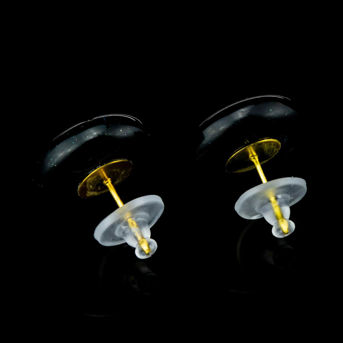 Gold post stud earrings with green glass tops on black background