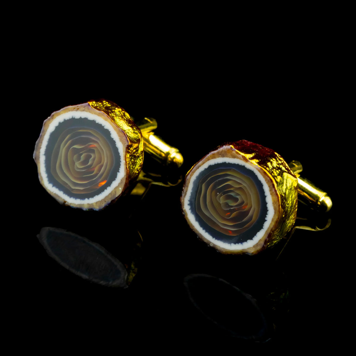 Pair of golden agate cufflinks with layered stone detail on a black background