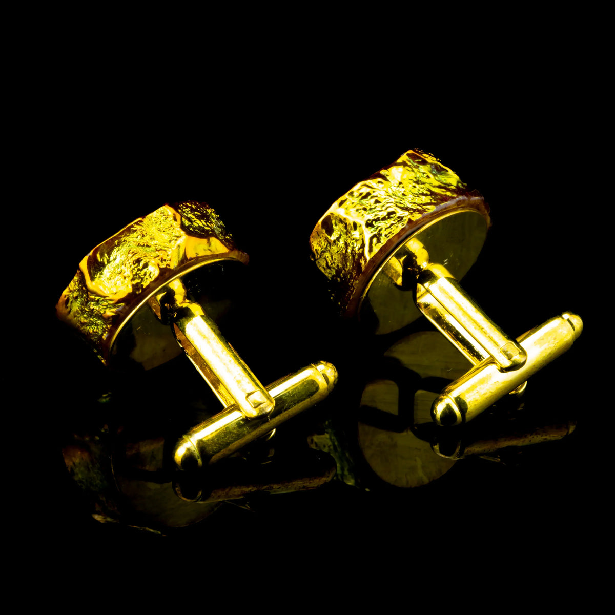 Gold agate cufflinks with textured design on a reflective black background
