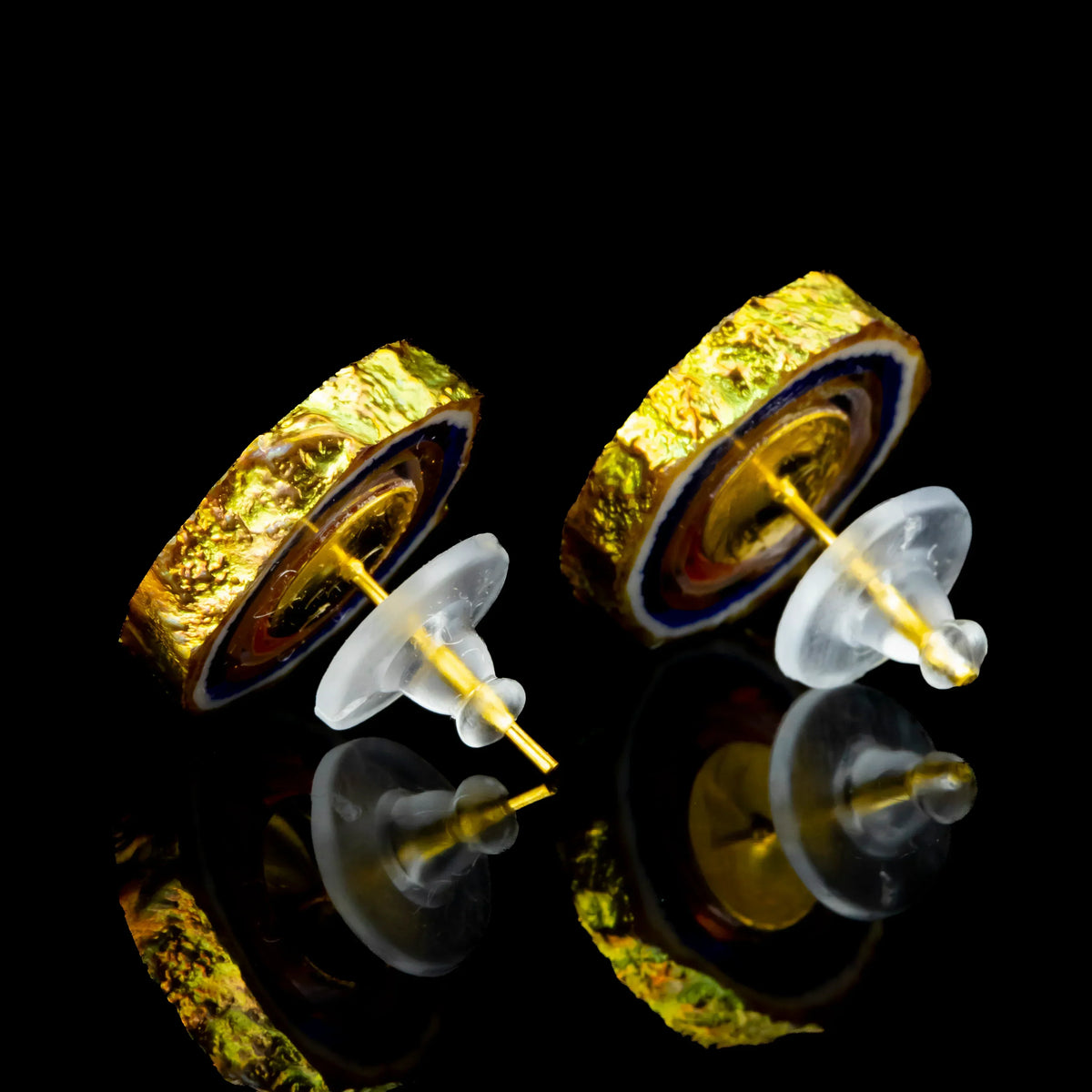 Golden agate stud earrings with textured edges and plastic backs on a black background