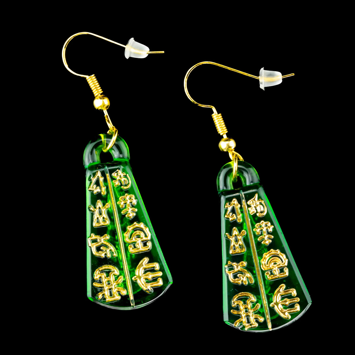 Green glass earrings with gold tablet designs and hook backs on black background