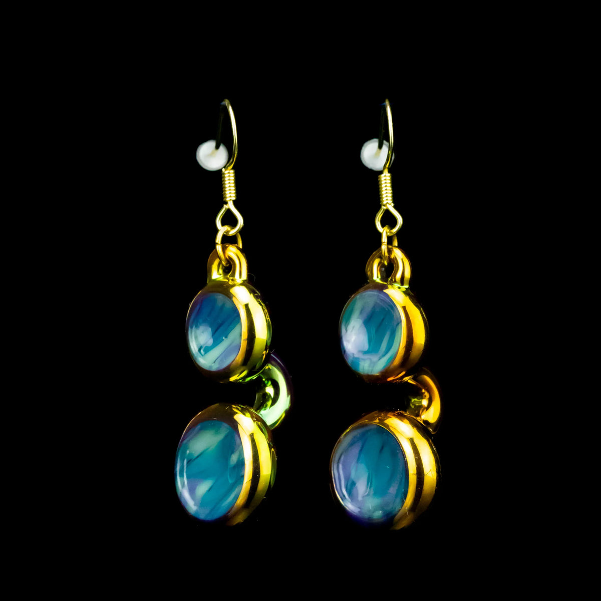 Gold dangle earrings with blue glass cabochons on a black background