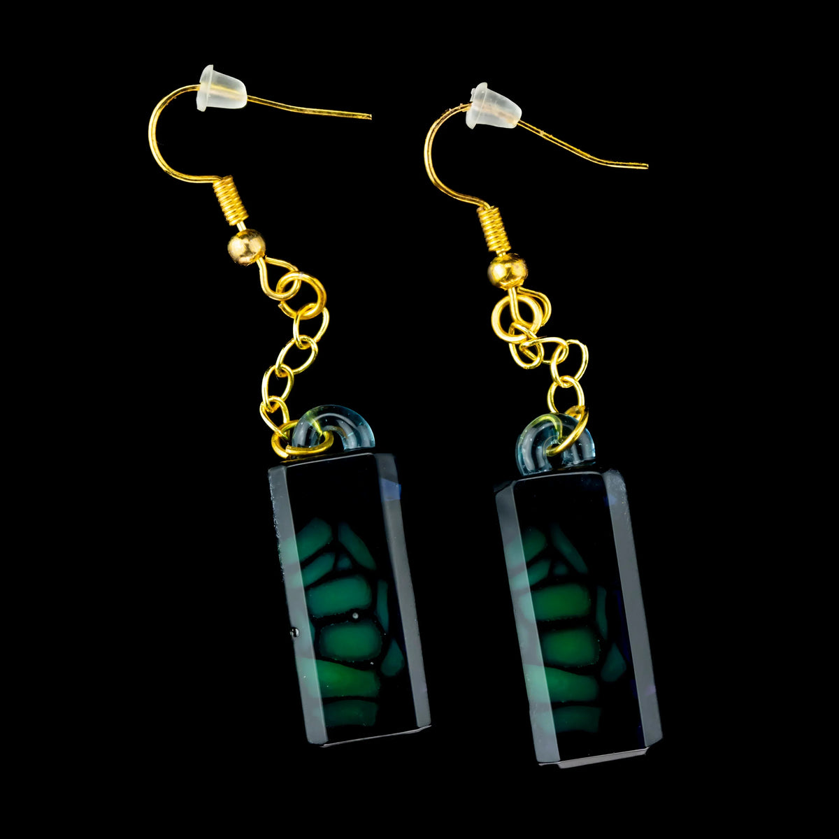 Green stained glass dangle earrings with gold hooks on black background