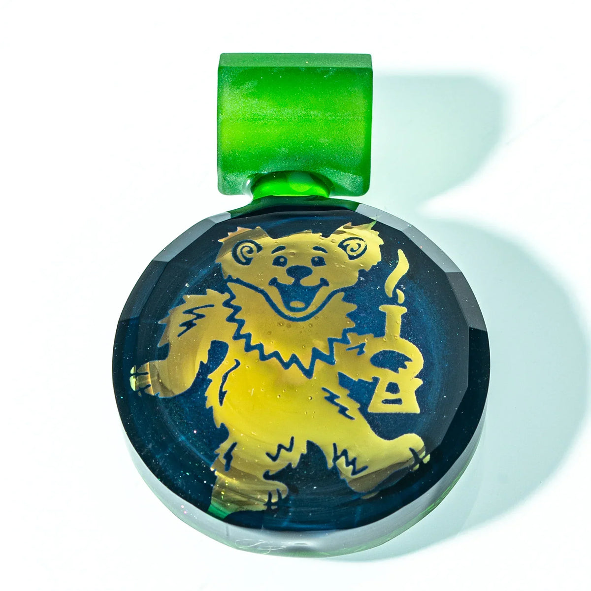 Glass pendant with yellow bear holding a pipe on blue background and green loop