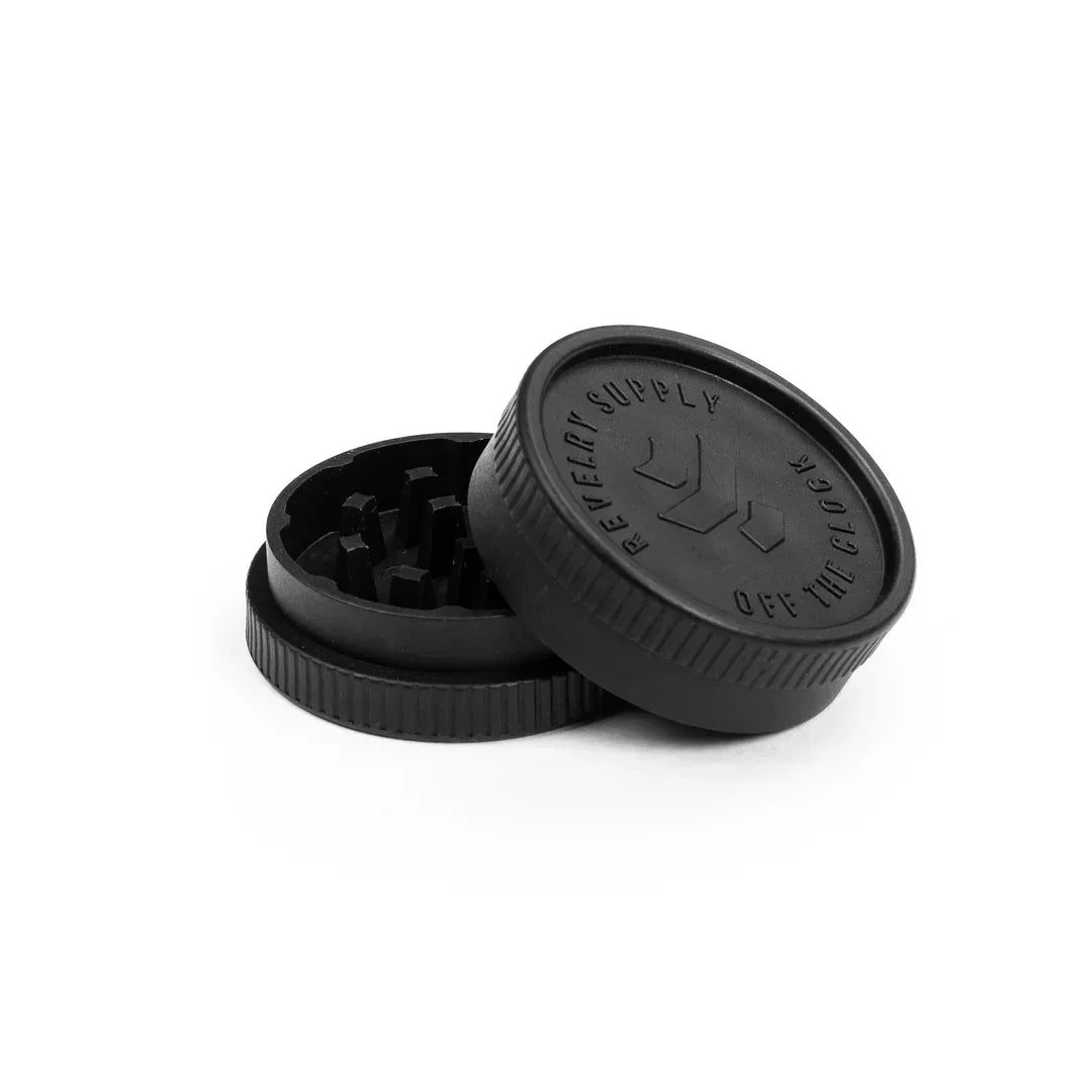 Matte black herb grinder with textured lid and sharp teeth, isolated on white background.