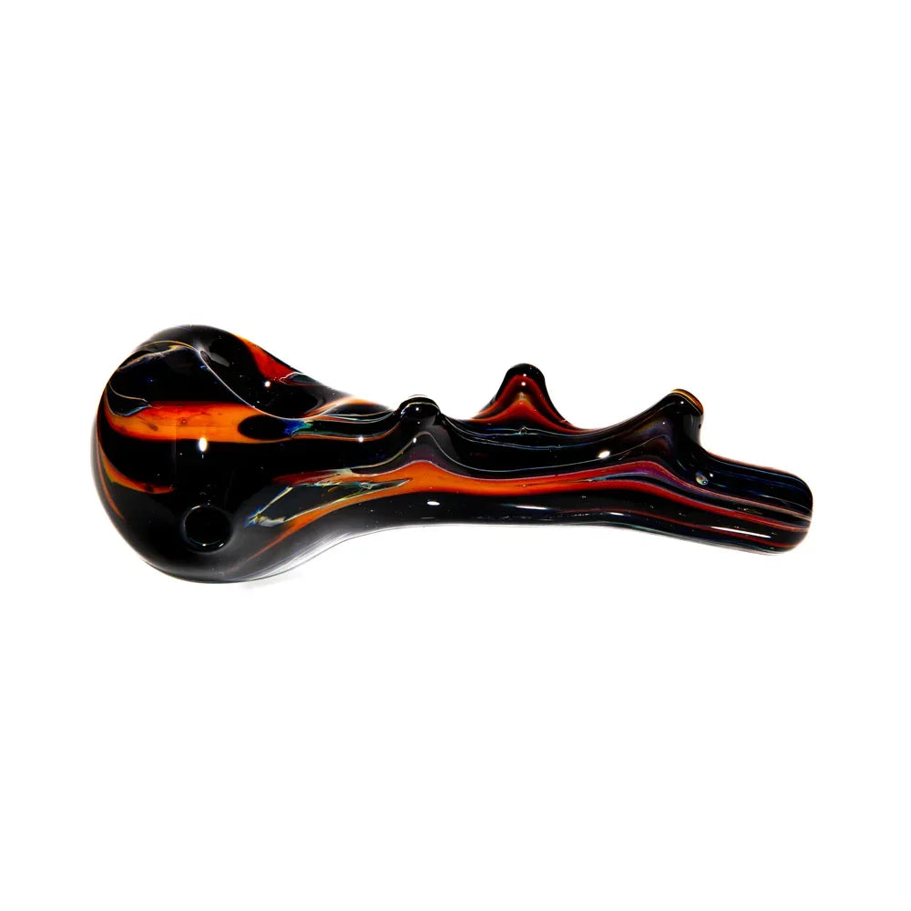 Hand-blown glass spoon pipe with black, orange, and red swirls on white background.