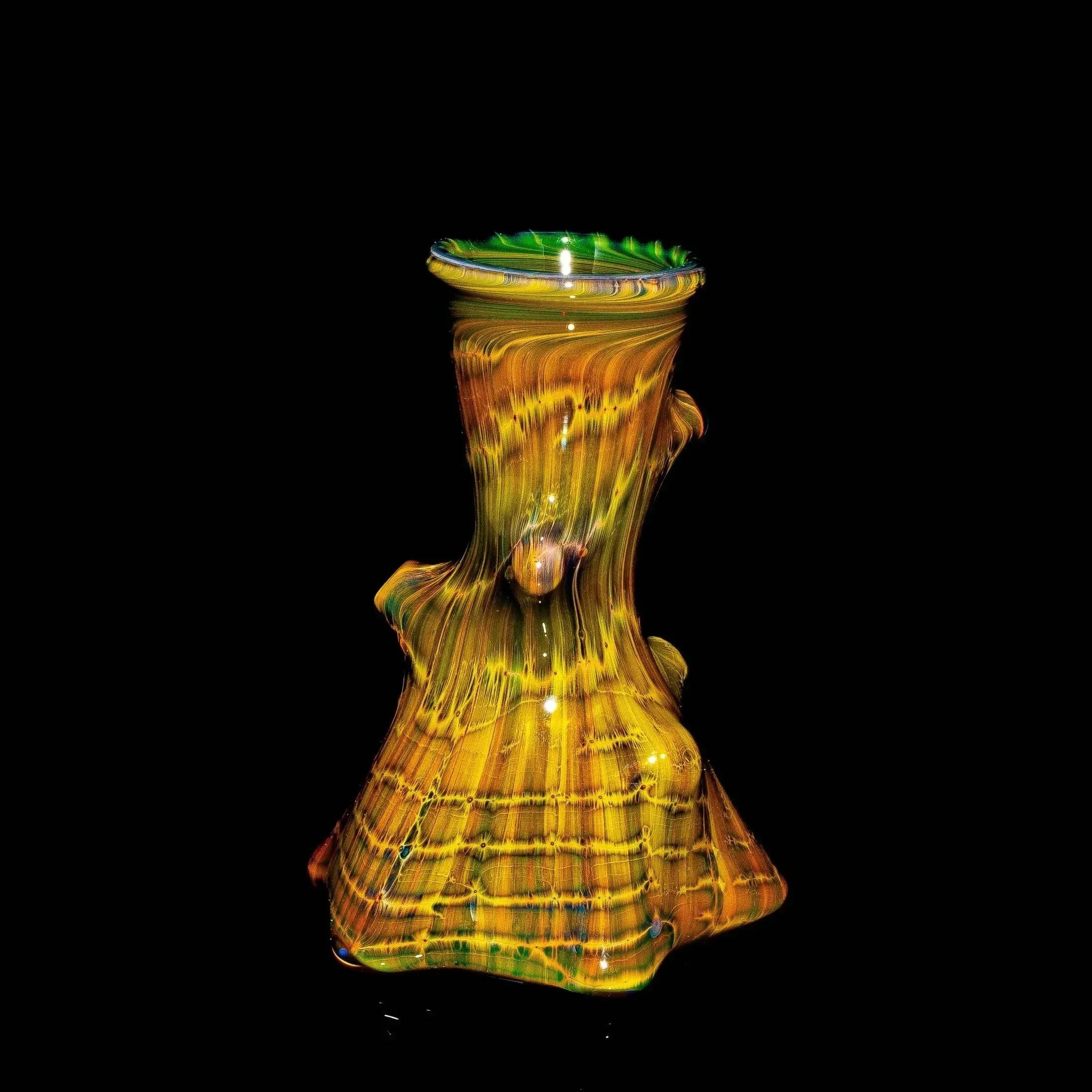Hand-blown glass water pipe with tree trunk design, yellow and green colors on black background