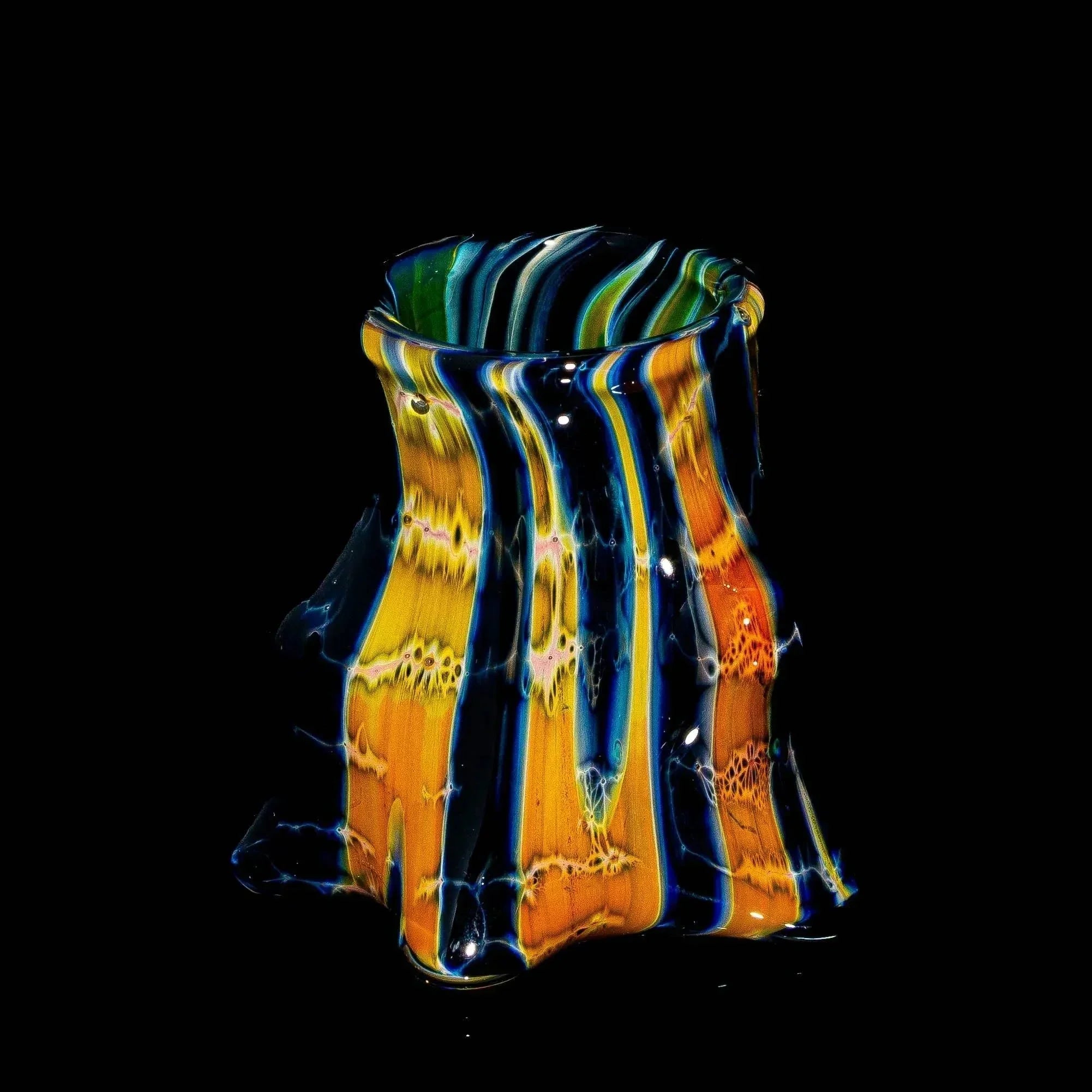 Handcrafted small glass stand with vibrant orange, blue, and yellow swirls on black background