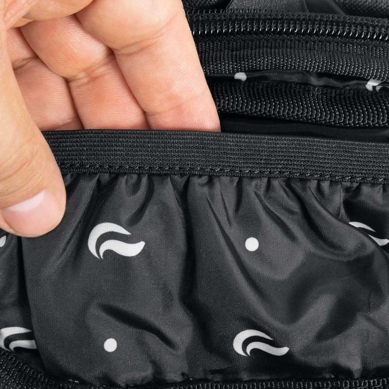 Close-up of hand opening black zippered bag with inner pocket and patterned lining