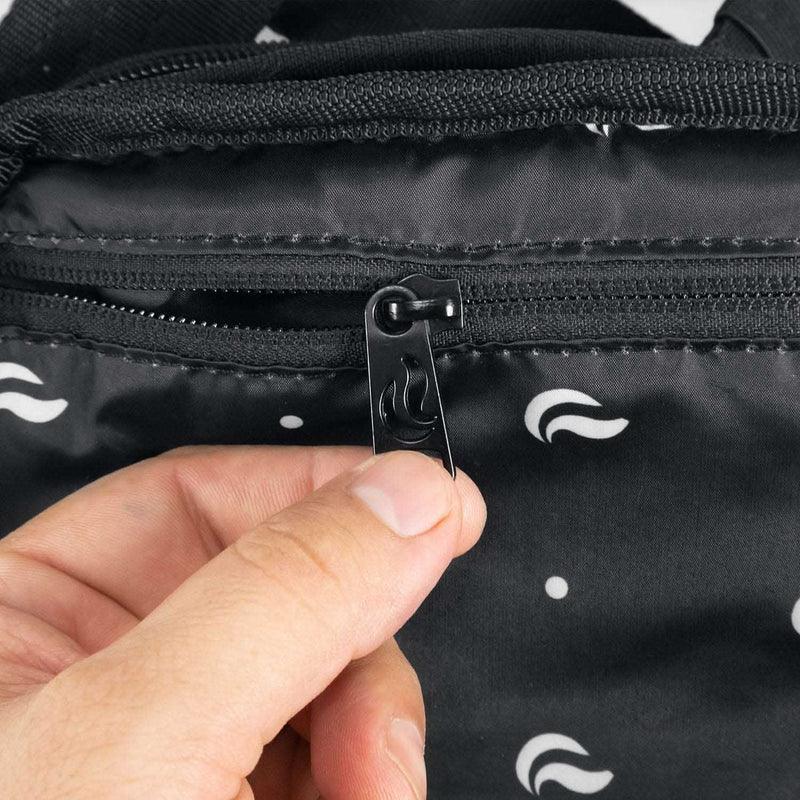 Close-up of hand holding black zipper on odor-proof bag with white pattern