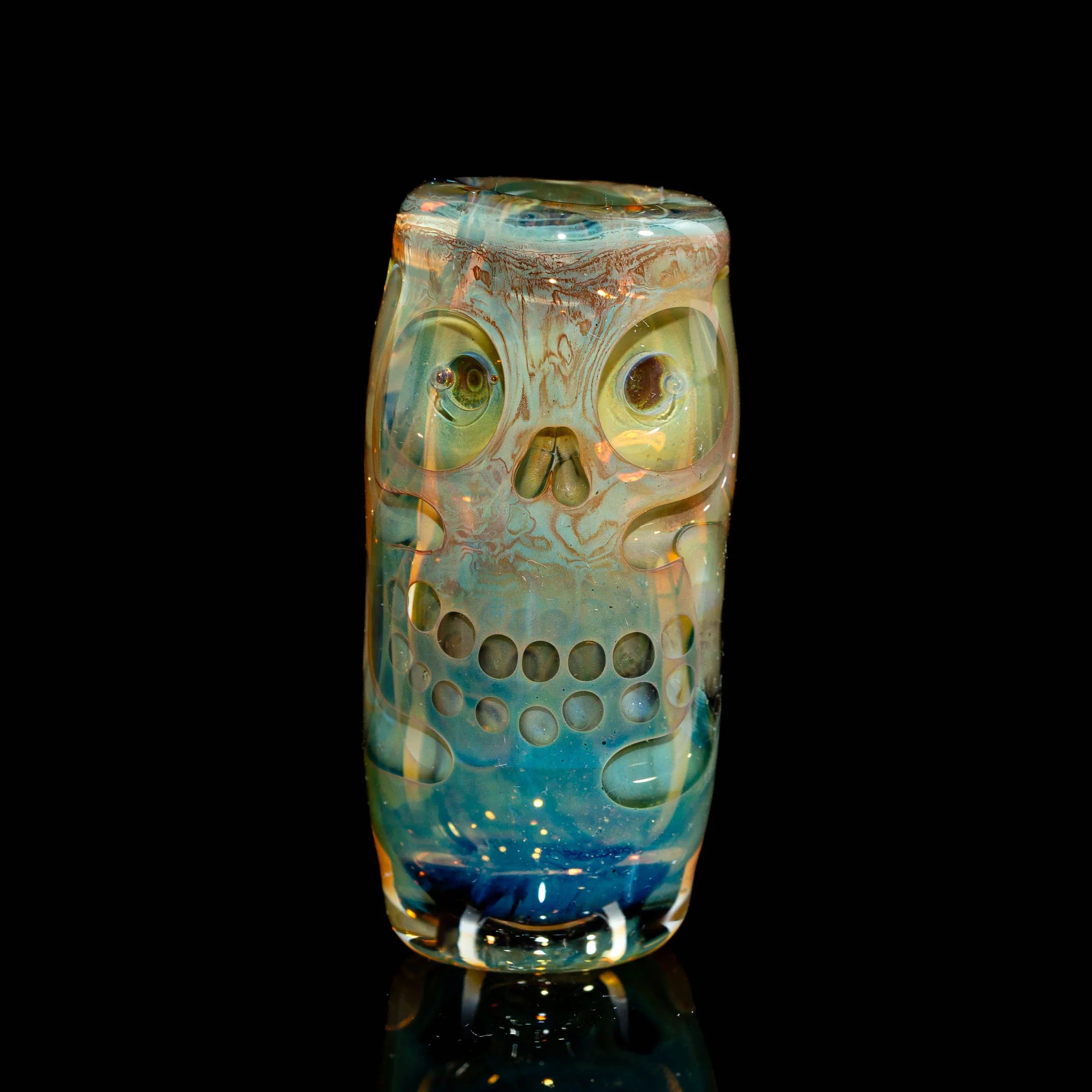 Hand-blown glass art pipe with intricate skull design and blue gradient on black background