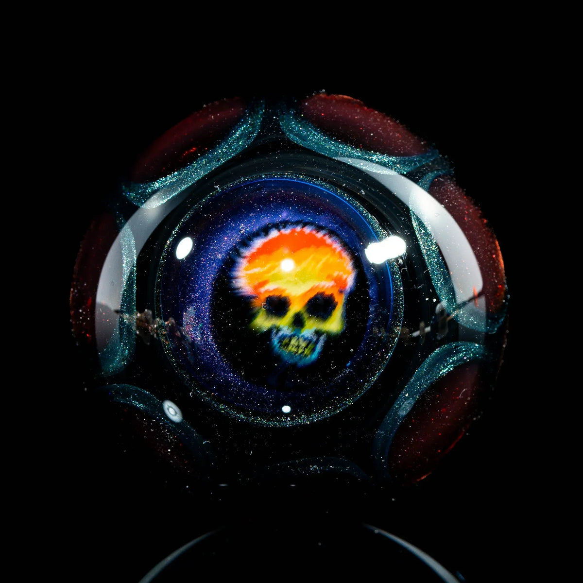 Colorful skull design inside a glass marble with sparkling accents on black background