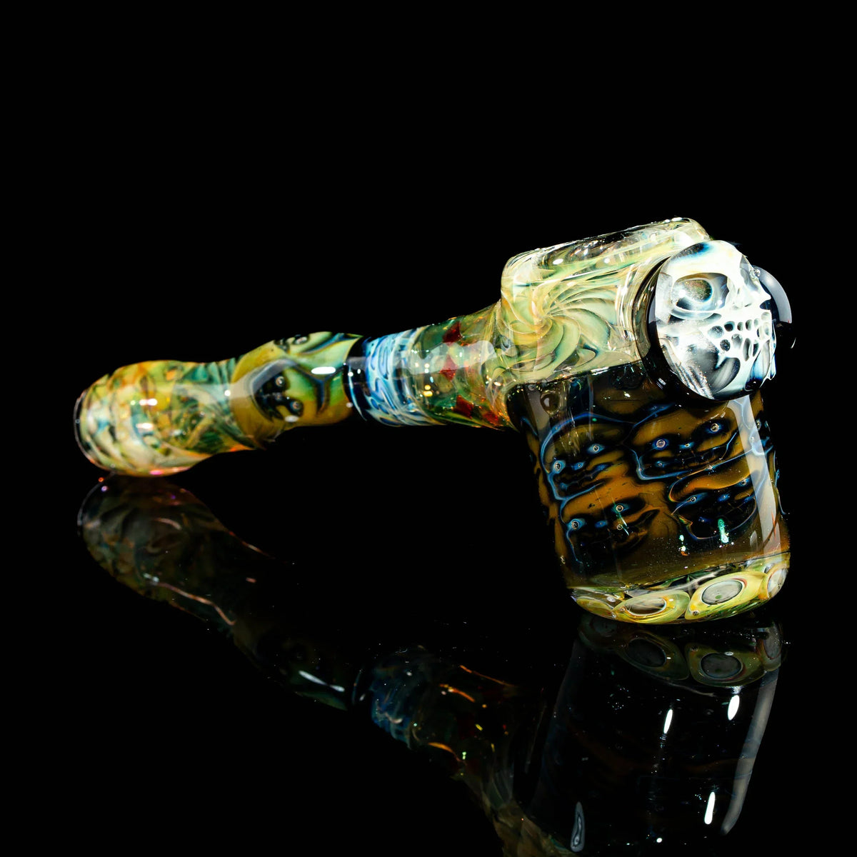 Heady glass hammer pipe with intricate skull and face designs on glossy black background