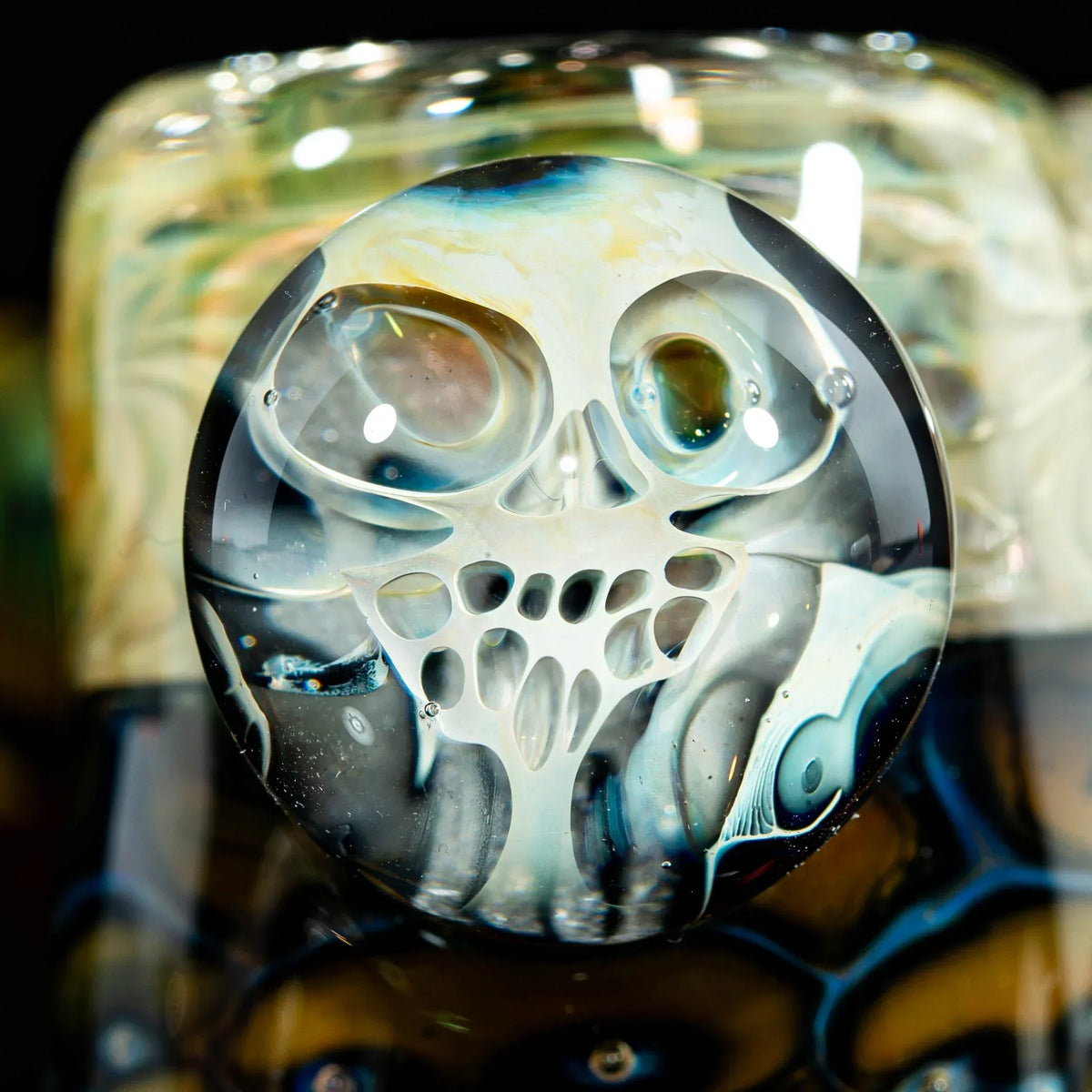 Close-up of heady glass art featuring a detailed skull design in blue and white.