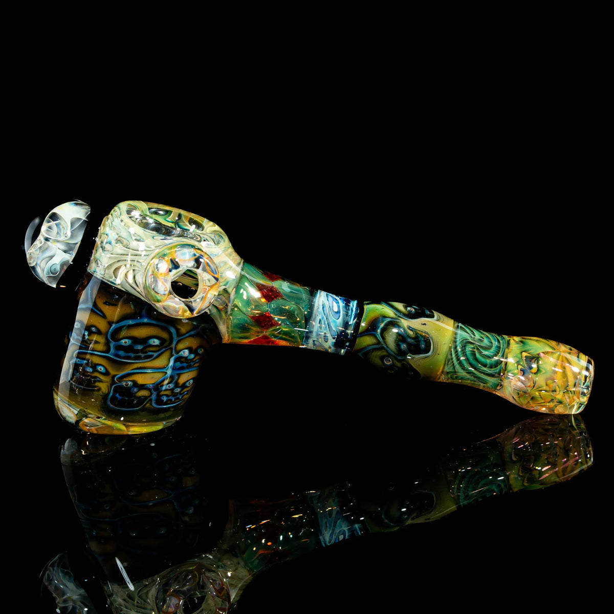 Colorful heady glass hand pipe with intricate patterns on a black reflective surface