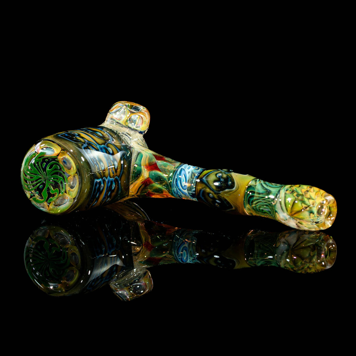 Colorful heady glass hand pipe with intricate designs on black reflective surface
