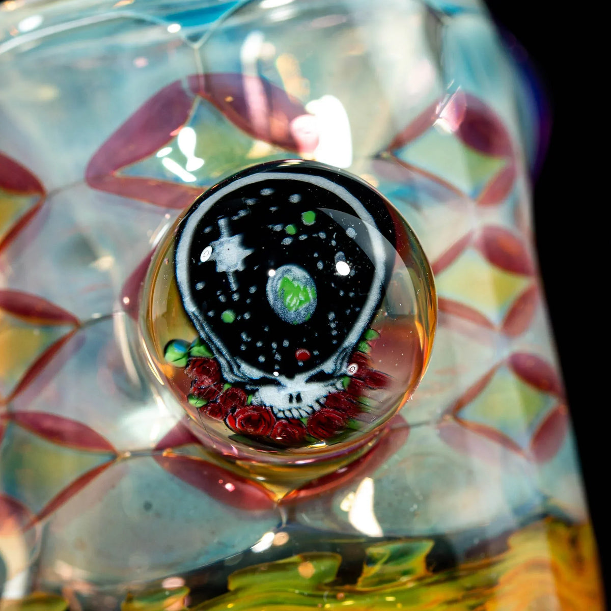 Hand-blown glass pipe with a skull and space motif, featuring vibrant color patterns.