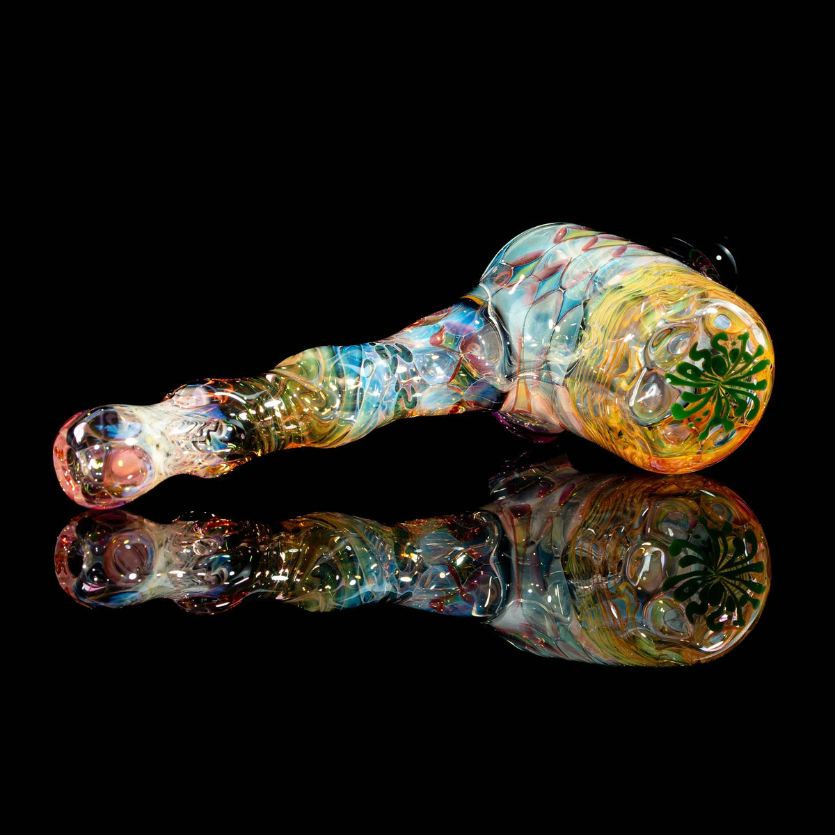 Colorful heady glass pipe with intricate patterns and leaf design on black reflective surface