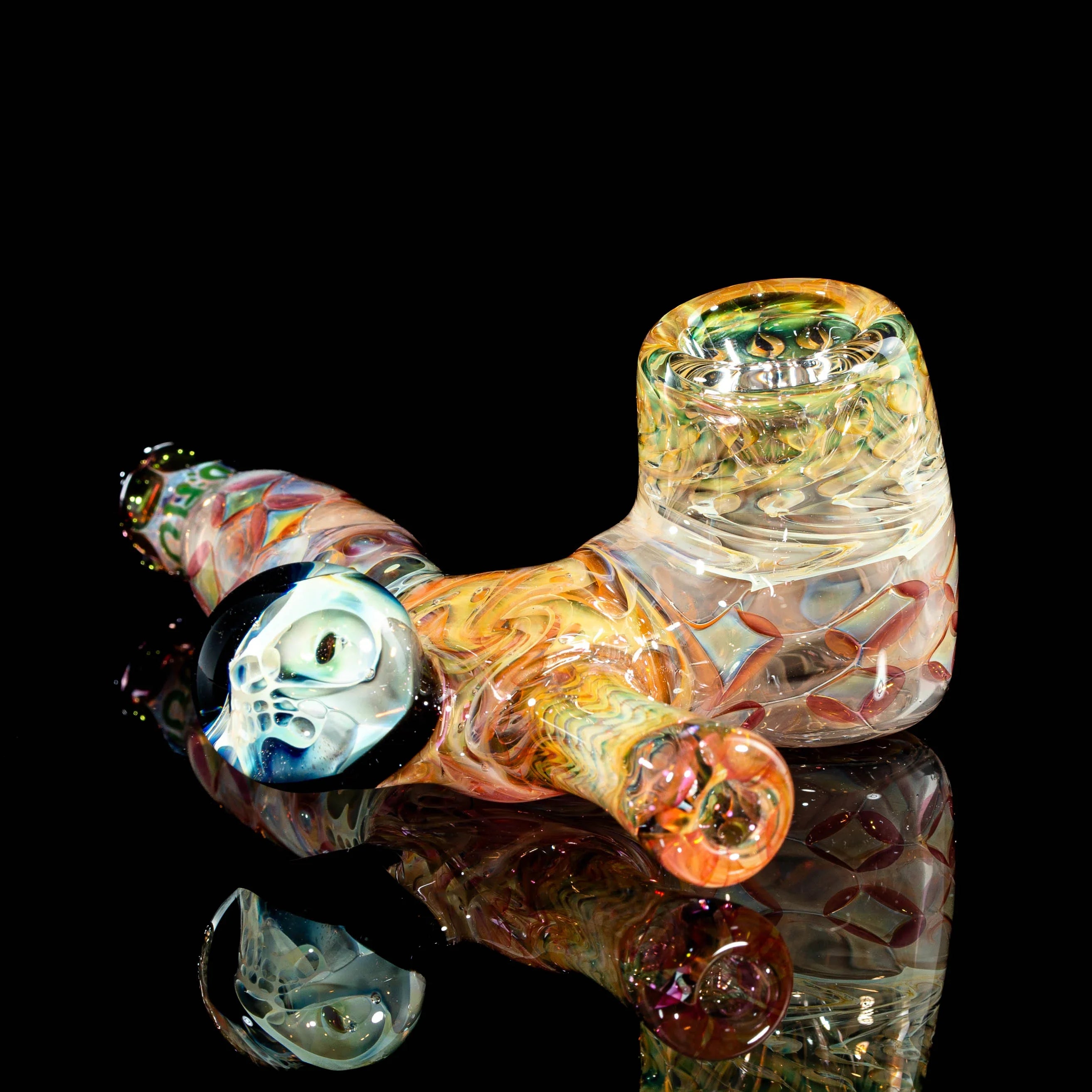 Artistic glass hand pipe with colorful swirls and a skull detail, displayed on black background