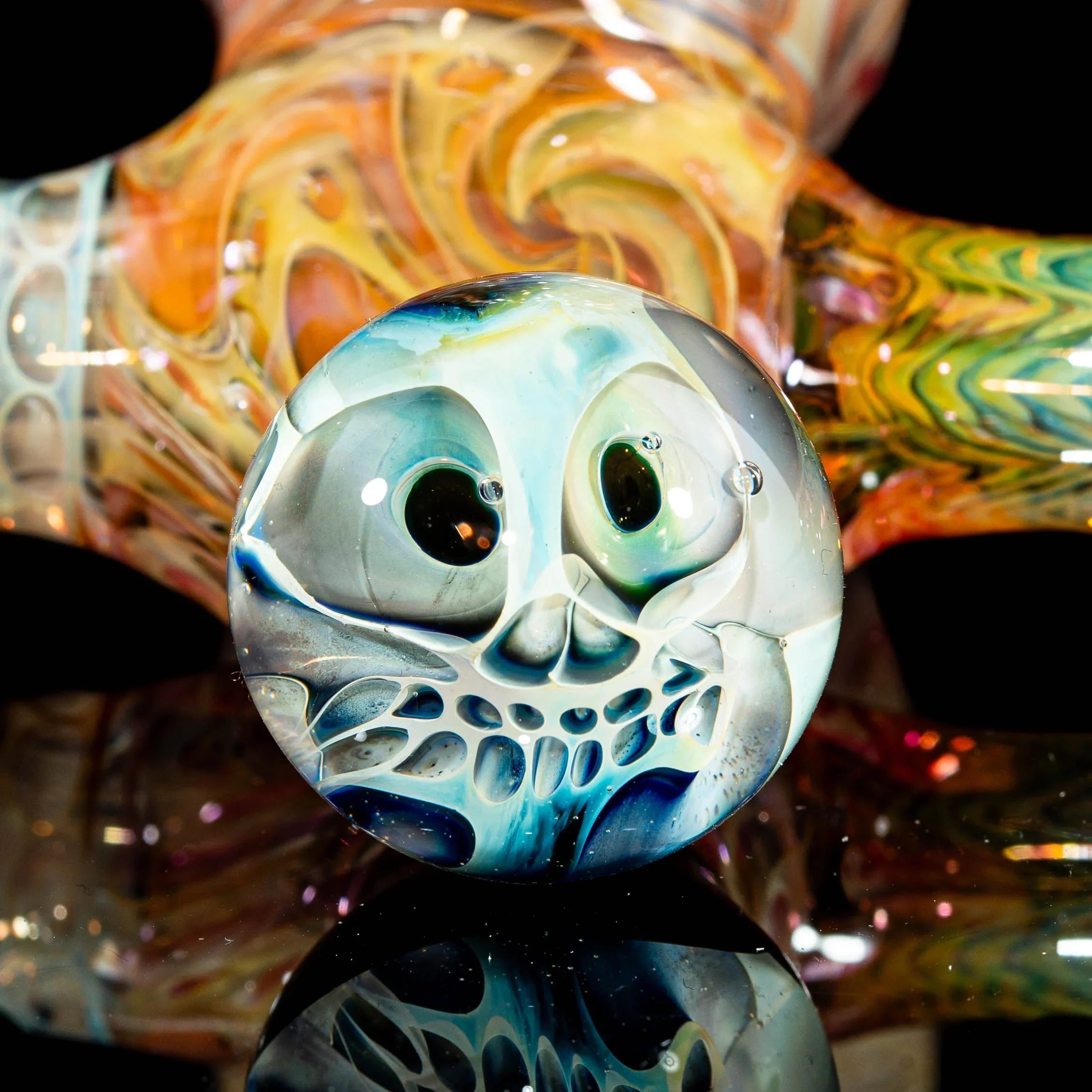 Hand-blown glass pipe with colorful swirling patterns and an intricate skull design