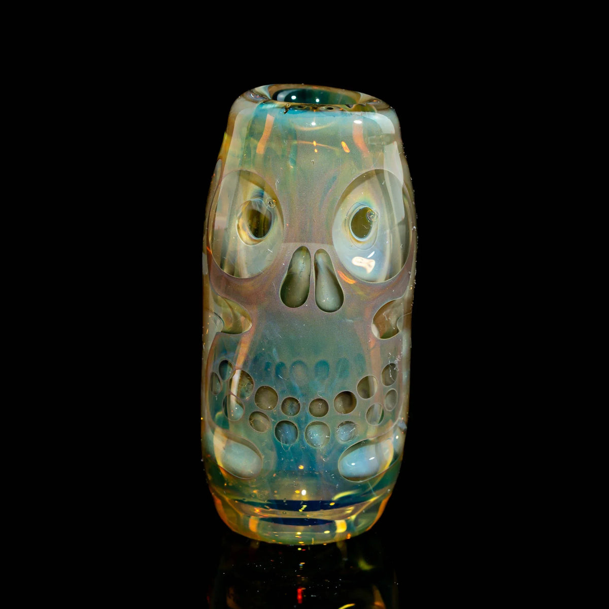 Handblown glass cup with iridescent skull design, artisan glass art under studio lighting