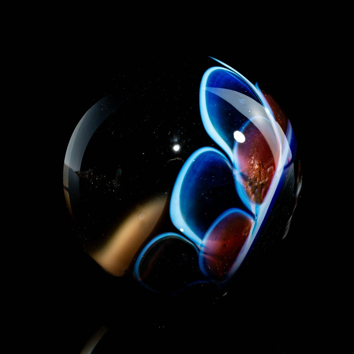 Heady glass marble with blue and red flame-like patterns on a black background