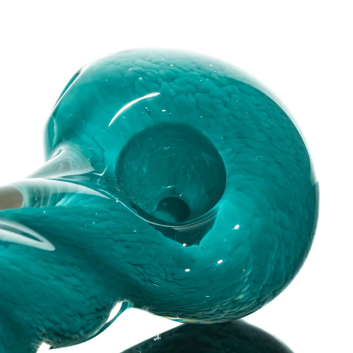 Close-up of a teal hand-blown glass spoon pipe with fritted texture and twist design