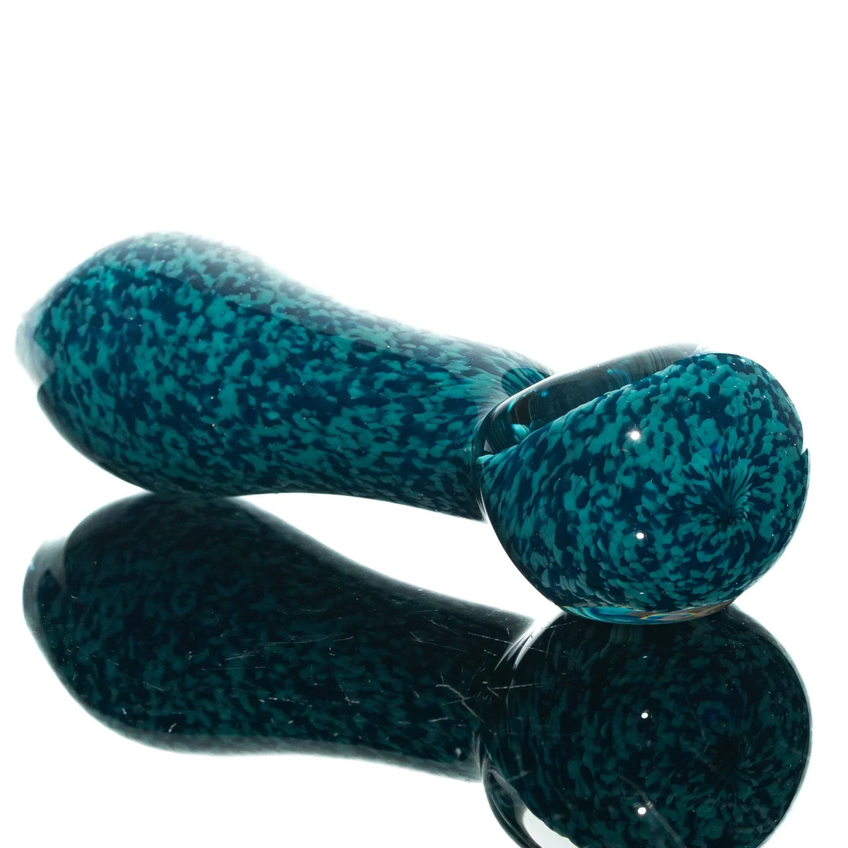 Aqua blue glass spoon pipe with peacock frit pattern on a reflective surface