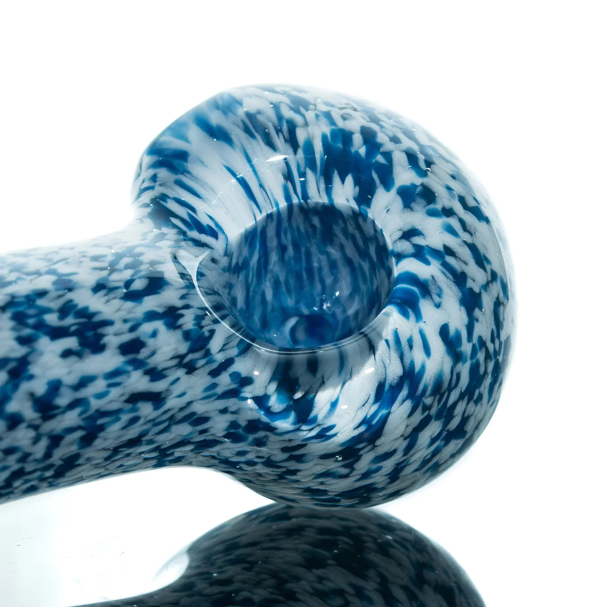 Blue and white frit glass spoon pipe with speckled pattern on a reflective surface