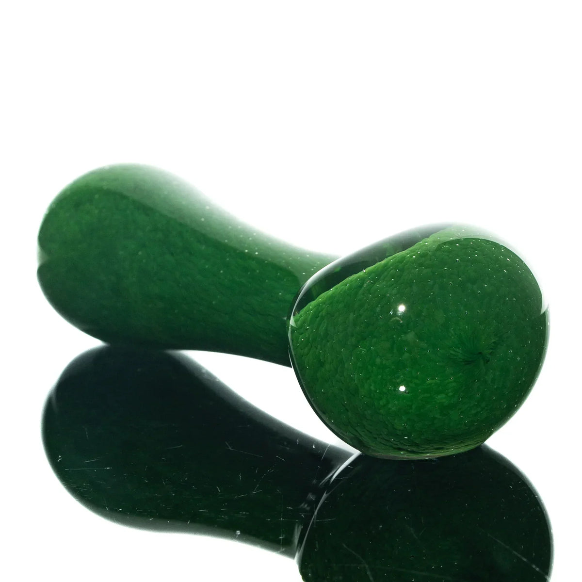 Green frit glass spoon pipe with glossy finish on a reflective surface