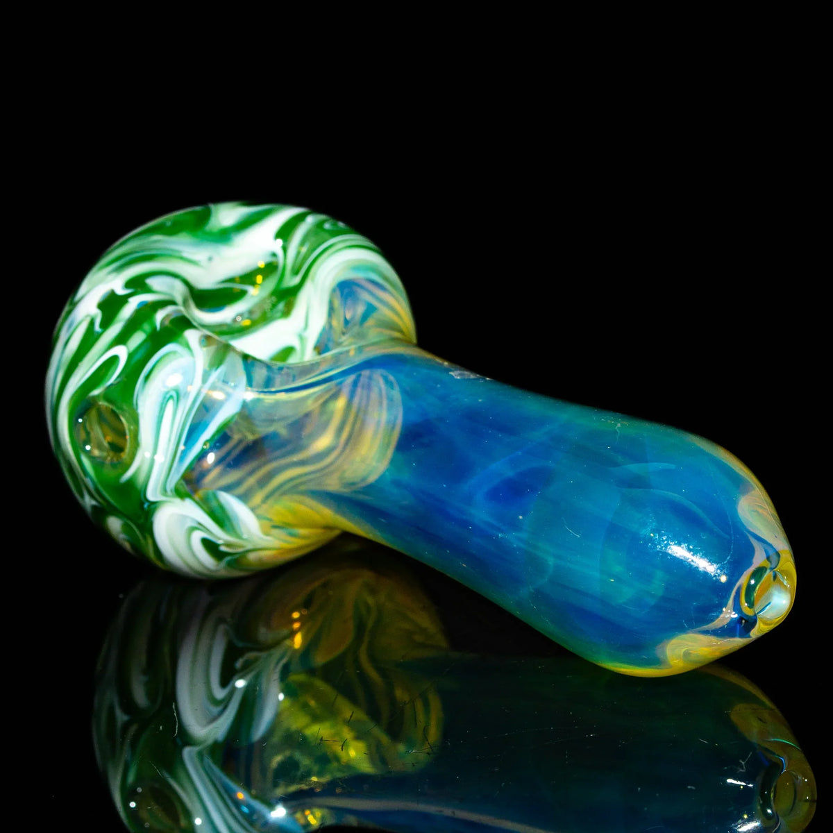 Handblown glass spoon pipe with green and white swirls and blue fume design on black background
