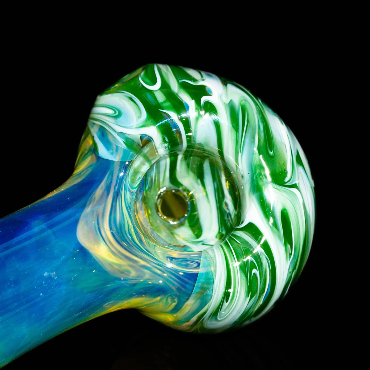 Green and white fumed glass spoon pipe with colorful swirls on a black background