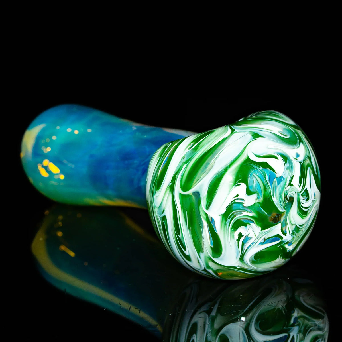 Green and white glass hand pipe with blue handle, artistic swirl design, on black background