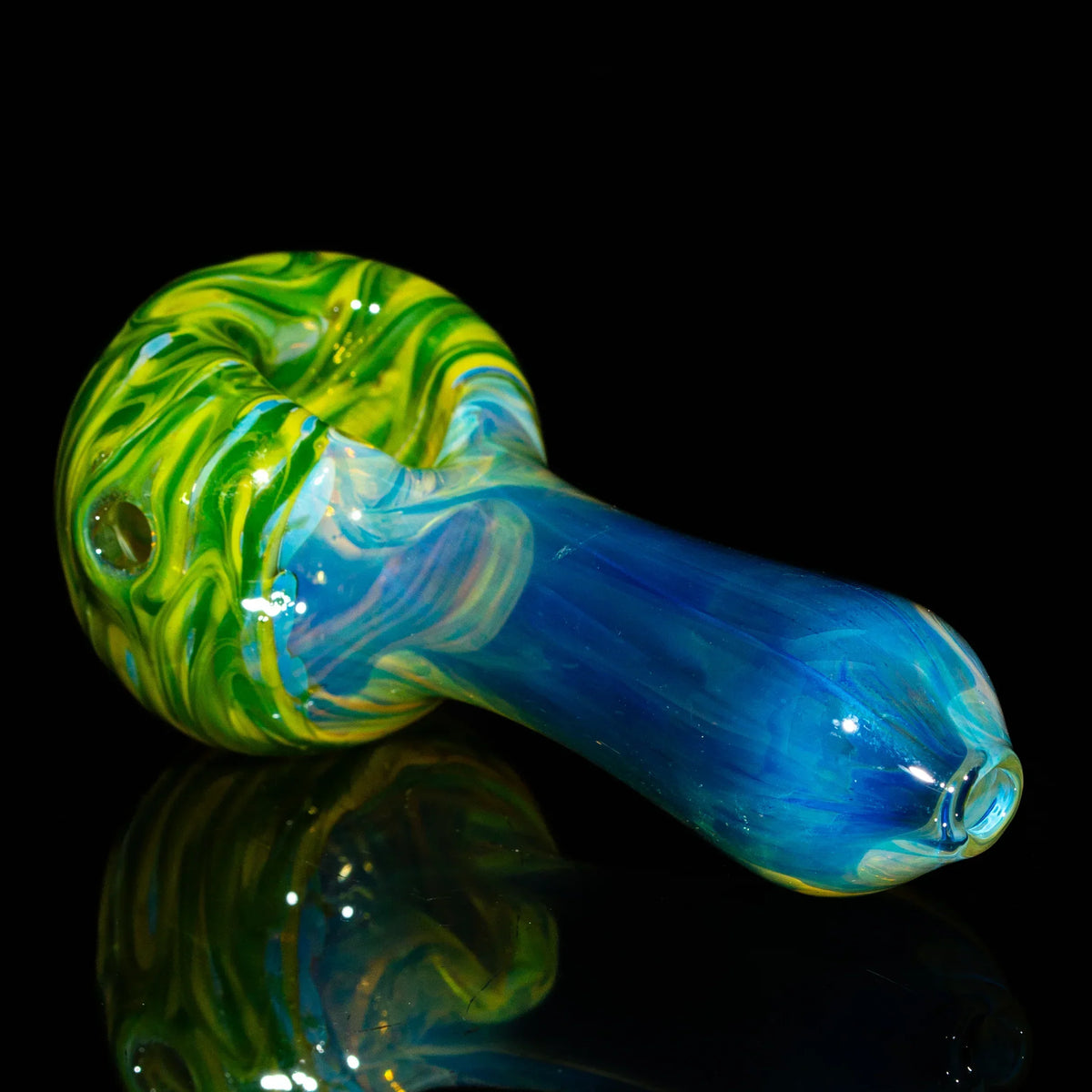 Hand-blown glass spoon pipe with green, yellow, and blue swirled design on black background