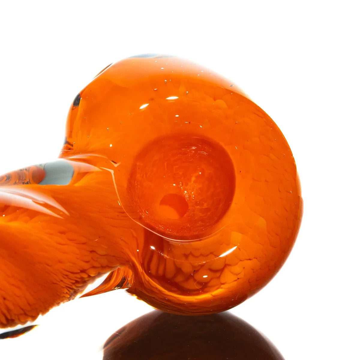 Orange glass spoon pipe with frit twist design on a white background