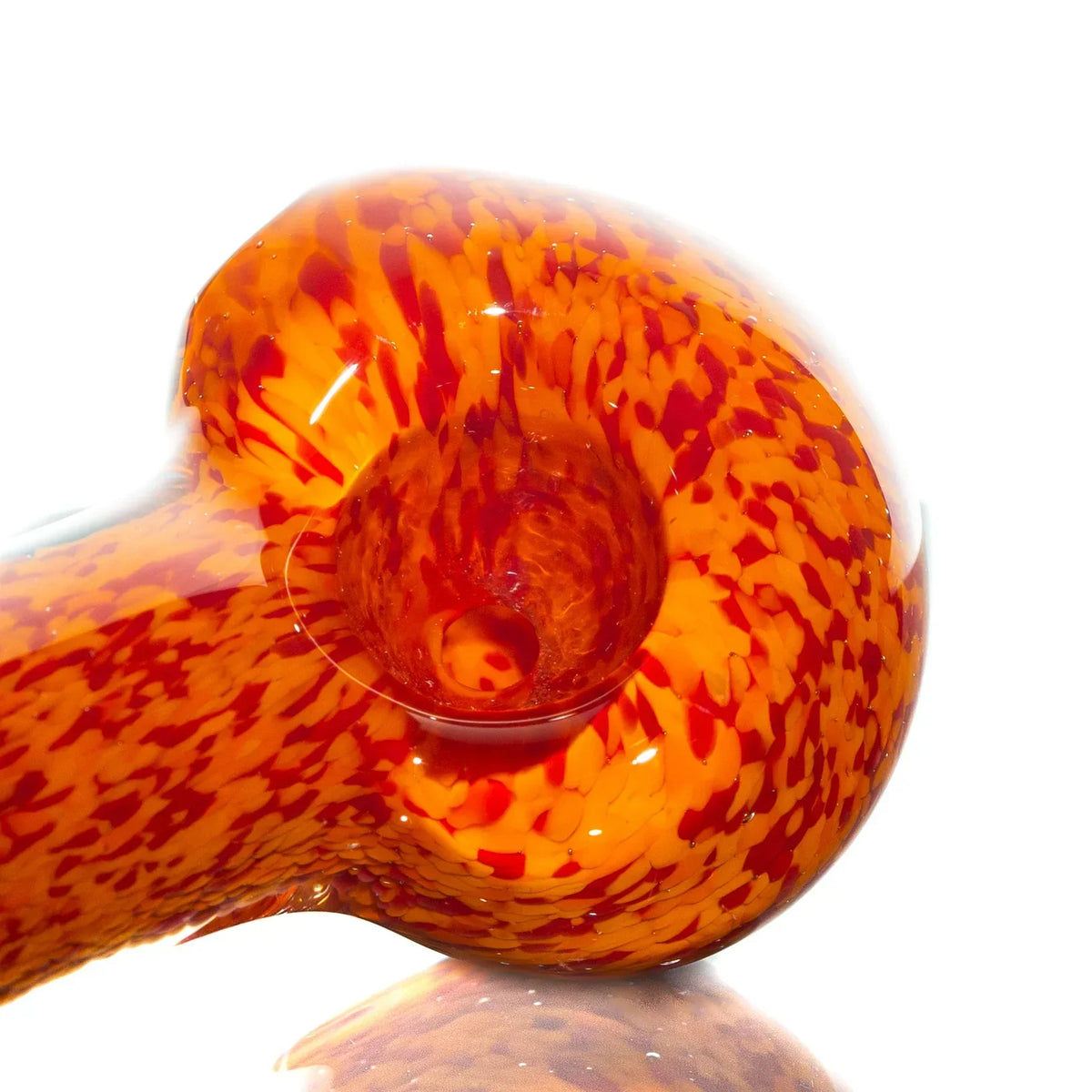 Hand-blown glass spoon pipe with vibrant orange and red frit design on a white background