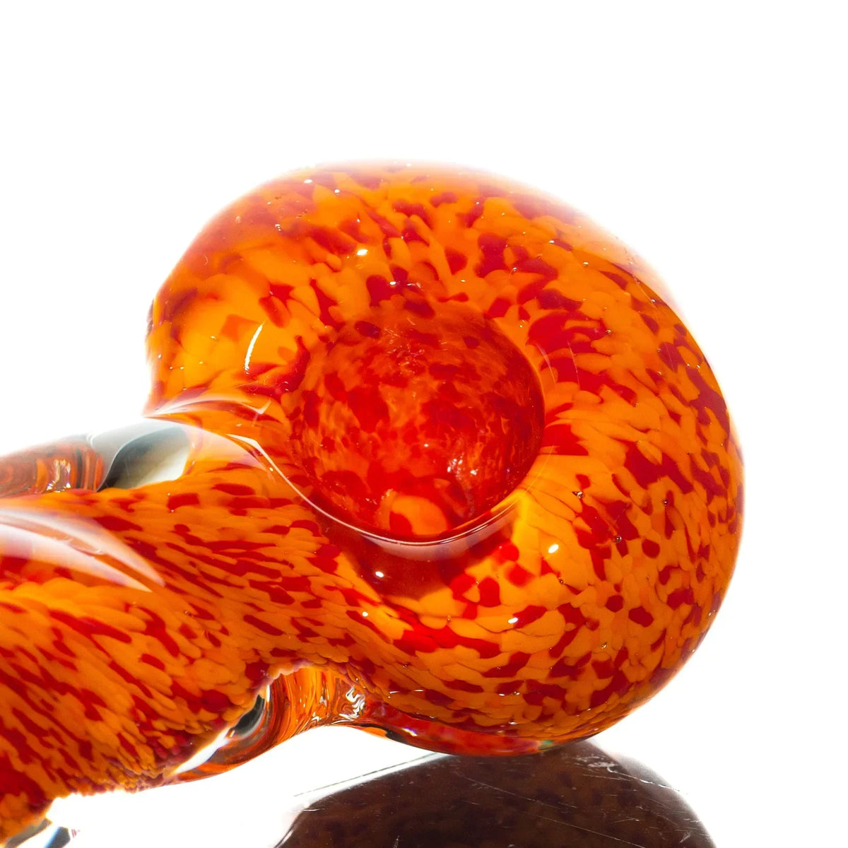 Close-up of an orange and red frit glass hand pipe with twisted design on white background
