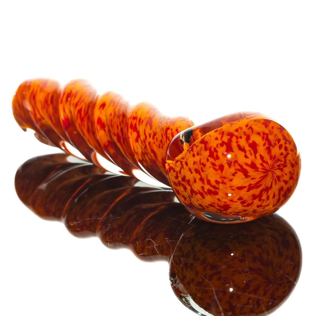 Hand-blown glass spoon pipe with orange and red frit twist design on reflective surface