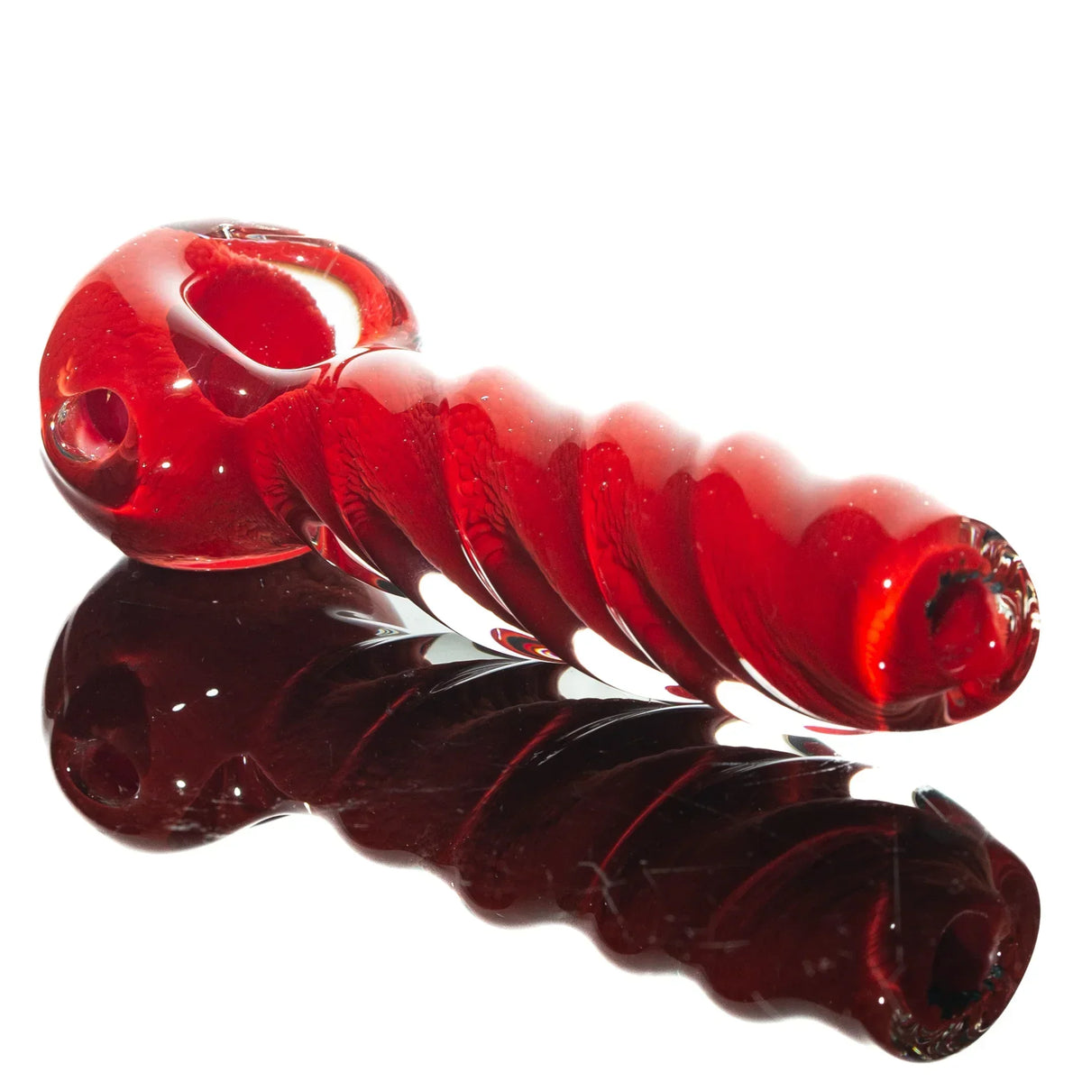 Red glass spoon pipe with twisted design on reflective surface