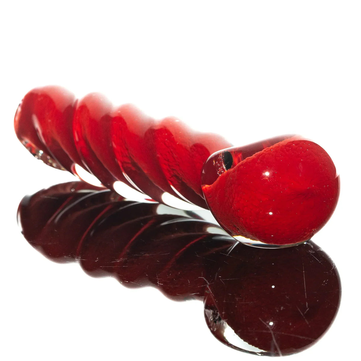 Red glass hand pipe with twisted frit design displayed on reflective surface