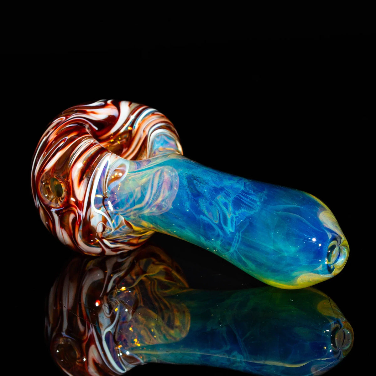 Hand-blown glass spoon pipe with red, white, and blue fume design, displayed on black.