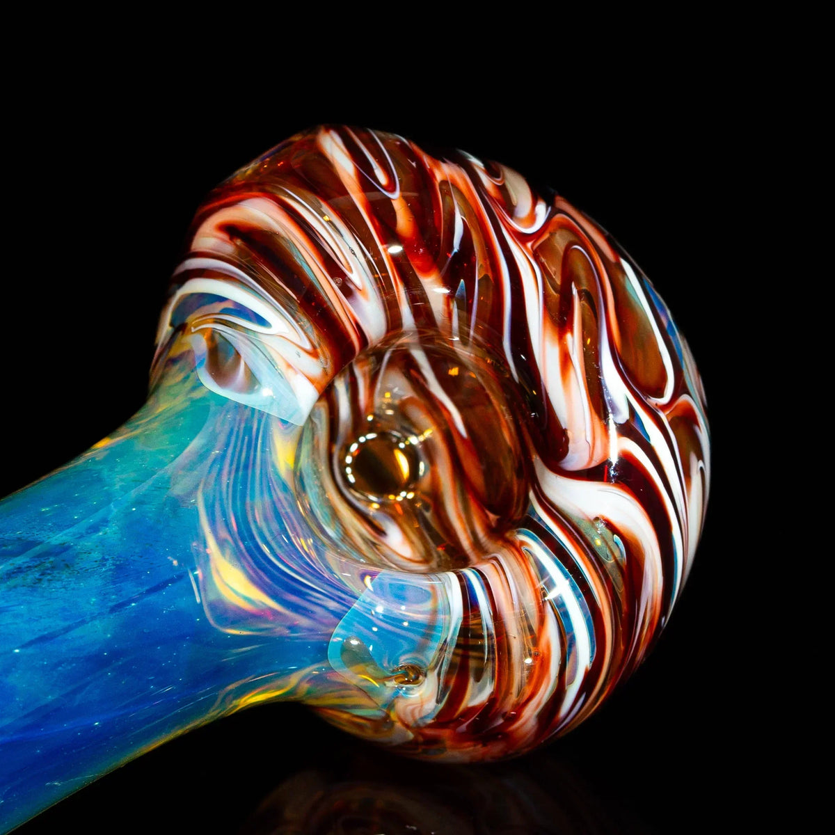Red and white fumed glass hand pipe with swirled bowl and blue stem on black background