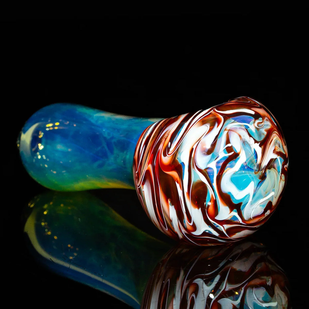 Red and white fumed glass spoon pipe with blue and yellow handle on black background