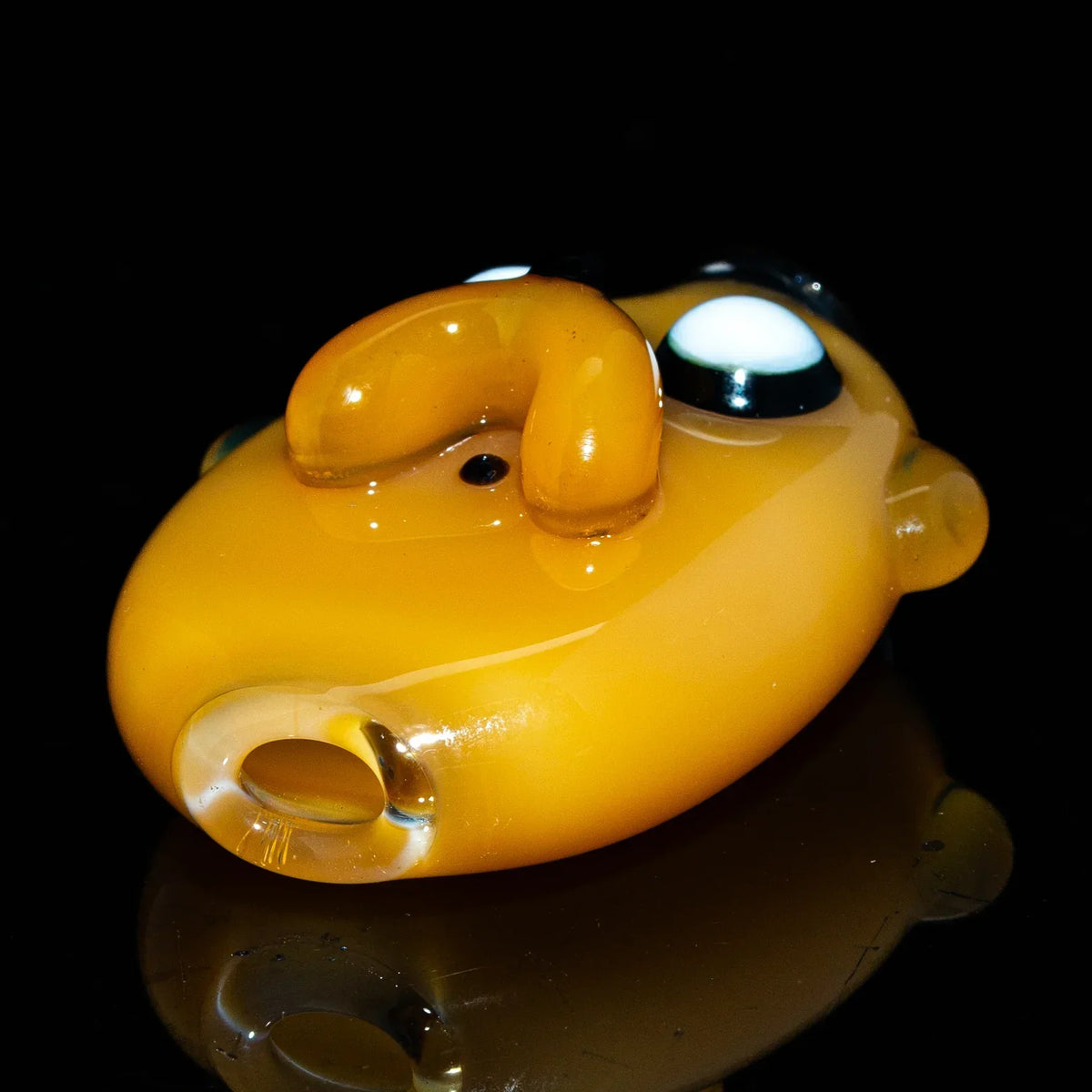 Yellow glass spoon pipe with whimsical face design, displayed on black background