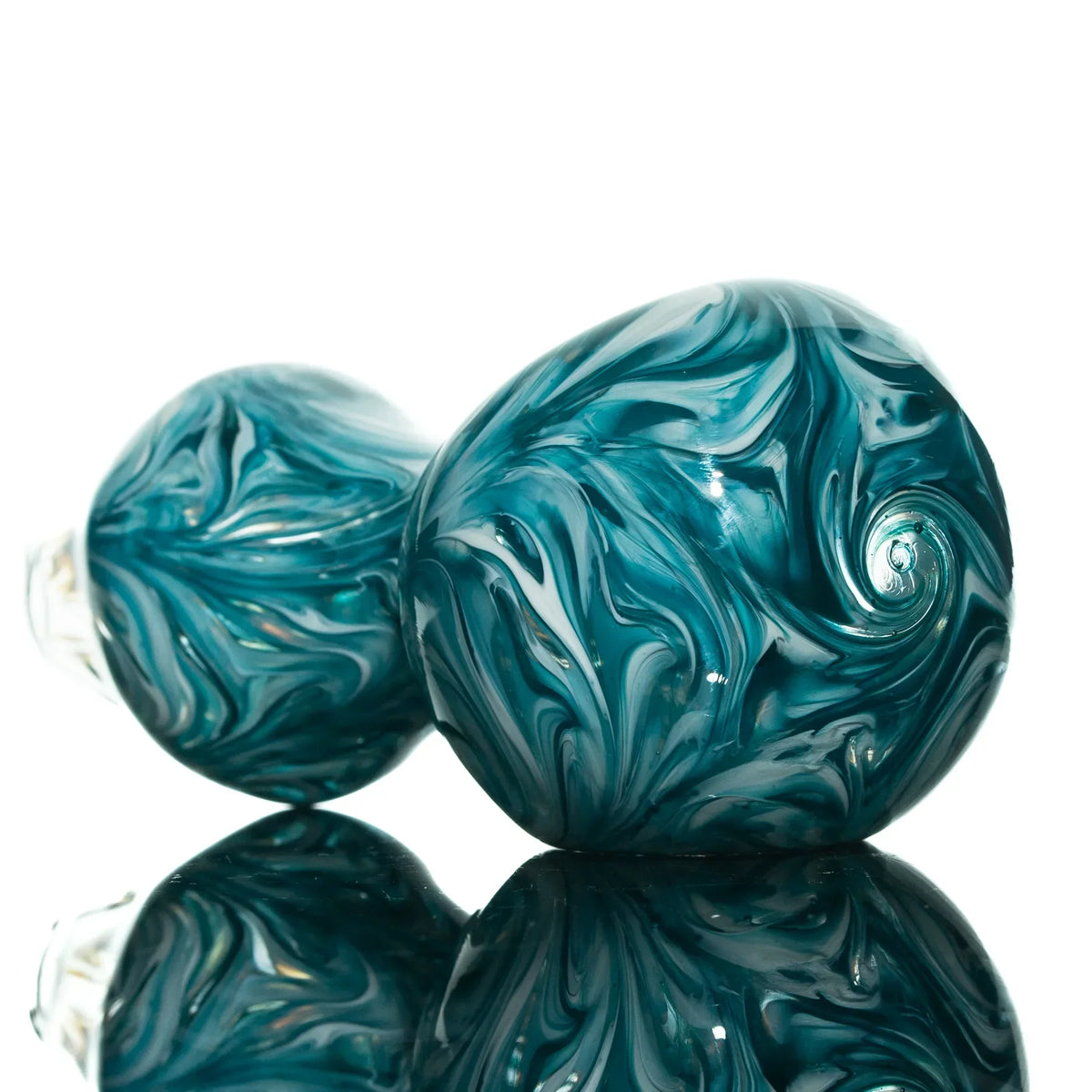 Teal and white glass hand pipe with hourglass shape and swirl design, on reflective surface